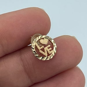 May include: Gold earring with a circular design featuring the word "LOVE" with a heart in the center. The earring has a diamond-cut edge.