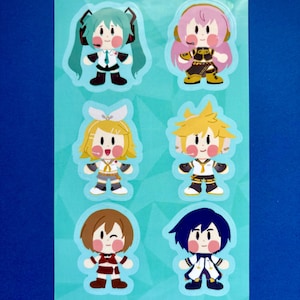 May include: A sheet of colorful stickers featuring six chibi-style anime characters with various hairstyles and outfits. The stickers are on a light blue background. The characters have large eyes and rosy cheeks.