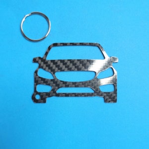 May include: A silver metal car keychain with a carbon fiber pattern. The keychain is shaped like the front of a car.