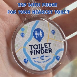 May include: A round, clear plastic keyring featuring a map graphic with blue toilet location pins. The text reads: TAP WITH PHONE FOR YOUR NEAREST TOILET, TOILET FINDER, and TAP WITH YOUR PHONE with a wireless signal icon in the centre.