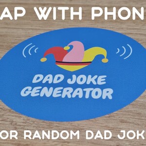 Op de afbeelding: Een blauwe ronde sticker met een narrenmuts en de tekst "DAD JOKE GENERATOR" en "TAP WITH PHONE" erboven en "FOR RANDOM DAD JOKE" eronder.