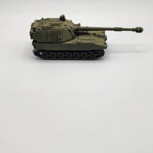 May include: A green toy model of a self-propelled howitzer, a type of artillery.