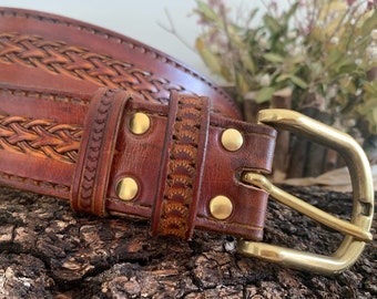 Cinturón de cuero repujado color marrón de 3.5 cm de ancho, con hebilla de zamak. Posibilidad de personalizar el cinturón con las iniciales.