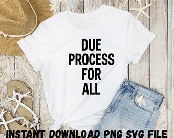 Op de afbeelding: Wit T-shirt met zwarte tekst die "Due Process For All" luidt. Het shirt ligt op een houten oppervlak met een spijkerbroek en een strohoed.