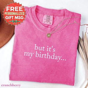 Może przedstawiać: Różowa koszulka Comfort Colors z białym napisem "but it's my birthday...". Złoty naszyjnik z wisiorkiem spoczywa na koszulce. Koszulka w rozmiarze S-P-CH.