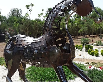 May include: A large metal sculpture of a horse, made from recycled metal pieces. The horse is standing on a metal base and is in a garden setting.