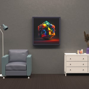 May include: A framed abstract art print featuring a colorful, exploded cube with a black background. The print is hanging on a gray wall above a white dresser with drawers and a gray armchair.