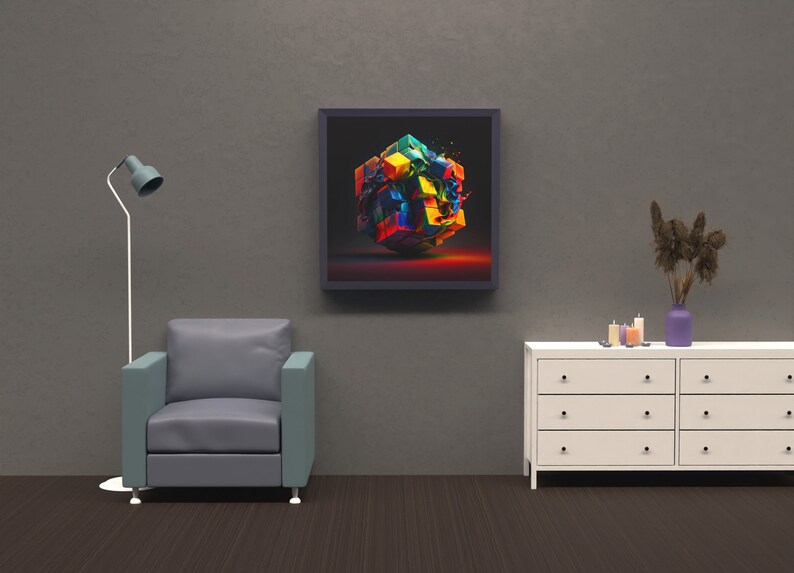 May include: A framed abstract art print featuring a colorful, exploded cube with a black background. The print is hanging on a gray wall above a white dresser with drawers and a gray armchair.