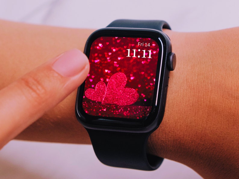 May include: A black smartwatch with a pink glitter background and a large pink heart on the screen. The time is 11:11 and the date is Fri 14.