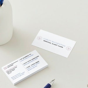 Customizable medical alert cards.  Includes, name, allergens, EMS instructions, conditions, medications, emergency contact, DOB.  Shows both sides of card on a desk with pencils around it.