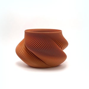 Peut inclure: Un vase en céramique de couleur terre cuite avec un design unique, tourbillonnant et côtelé. Le vase est fabriqué avec une imprimante 3D et a une finition lisse et mate.