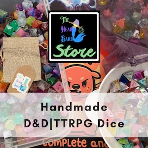 Op de afbeelding: Een verzameling veelkleurige polyhedrale dobbelstenen voor rollenspellen, inclusief een jute trekkoordzakje met een label met een zeemeerminlogo en de tekst The Head Bard Store. Een witte kom en doorzichtige bak bevatten diverse harsdobbelstenen.