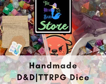 May include: A collection of multi-colored polyhedral dice for tabletop games, including a burlap drawstring bag with a tag featuring a mermaid logo and the text The Head Bard Store. A white bowl and clear container hold various resin dice.