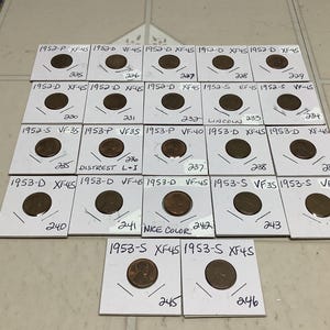 May include: A collection of 1952 and 1953 Lincoln pennies in various conditions, including XF-45, VF-45, VF-35, and EF-45. The coins are displayed on white cards with the year and grade written on each card.