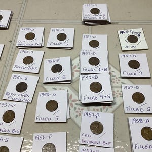 May include: A collection of white cards with coins on them. The cards have handwritten dates and descriptions of the coins, such as "Filled 9+5", "CUD Filled 5", and "Doubled Date Filled B".