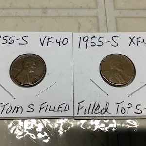 May include: Two 1955-S Lincoln pennies, one graded VF-40 and the other XF4S. The penny graded VF-40 has a filled-in 'S' mint mark on the bottom of the coin, while the penny graded XF4S has a filled-in 'S' mint mark on the top of the coin.