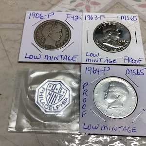 Può includere: Una tazza di ceramica bianca con manico nero e la scritta "But First, Coffee" in grassetto nero. La tazza è appoggiata su una superficie di legno. La tazza è alta 10 cm.