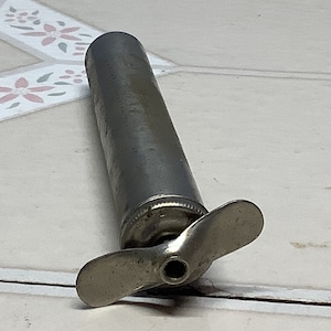 May include: A silver metal hand pump with a propeller-shaped handle. The pump is used to inflate bicycle tires.