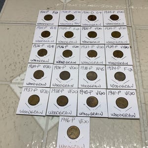 May include: A collection of vintage Woodgrain pennies, each encased in a white cardboard holder with handwritten details. The image displays various dates and grades, including 1920, 1925, 1926, 1929, 1930, 1934, 1937, 1938, 1940, 1941, and 1946.