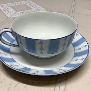 May include: A white teacup and saucer with a blue and white striped pattern. The cup has a wide, rounded bowl and a handle. The saucer has a matching pattern.