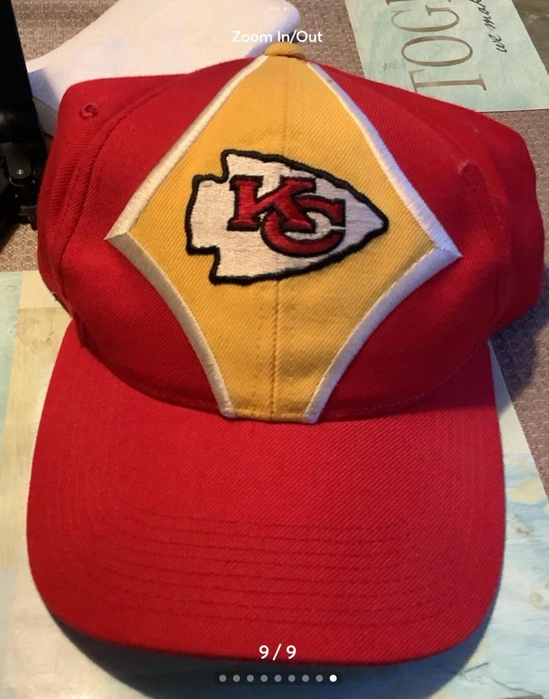 May include: Red and yellow baseball cap with a white and red Kansas City Chiefs logo. The logo is a stylized arrowhead with the letters "KC" inside.