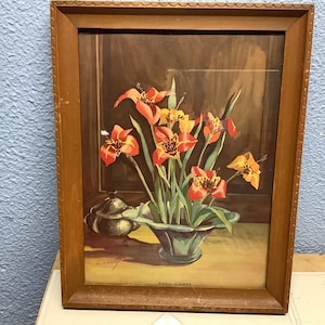 May include: A framed print of a floral still life. The artwork features orange and yellow flowers in a green vase, with a silver teapot on the left. The frame is made of wood and the text "SHELL FLOWER" is visible.