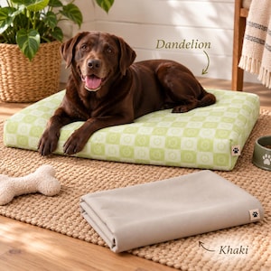 May include: A rectangular dog bed with a light green and white checkered pattern featuring a small paw print tag, accompanied by a folded solid khaki fabric cover with a matching paw print tag, both labeled Dandelion and Khaki respectively.