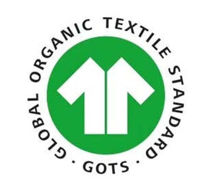 May include: A circular green and white logo with the text "GLOBAL ORGANIC TEXTILE STANDARD" around the perimeter. Inside the circle is a stylized white shirt icon. The letters "GOTS" are at the bottom.