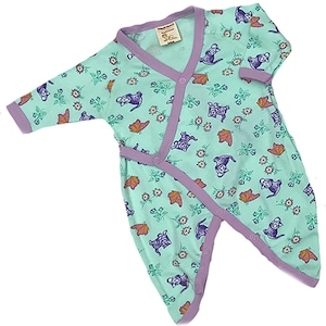 May include: A light green baby onesie with a purple trim and a wrap-around design. The onesie features a repeating pattern of small flowers, butterflies, and stylized animals.