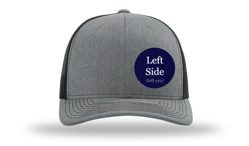 May include: A gray and black trucker hat with a navy blue circle patch that says "Left Side (left eye)".