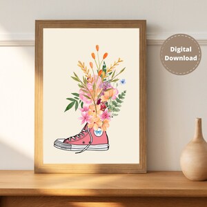 Puede incluir: Una zapatilla de lona rosa con un ramo de flores de acuarela que brotan de la parte superior. Las flores son rosas, naranjas, amarillas y azules.