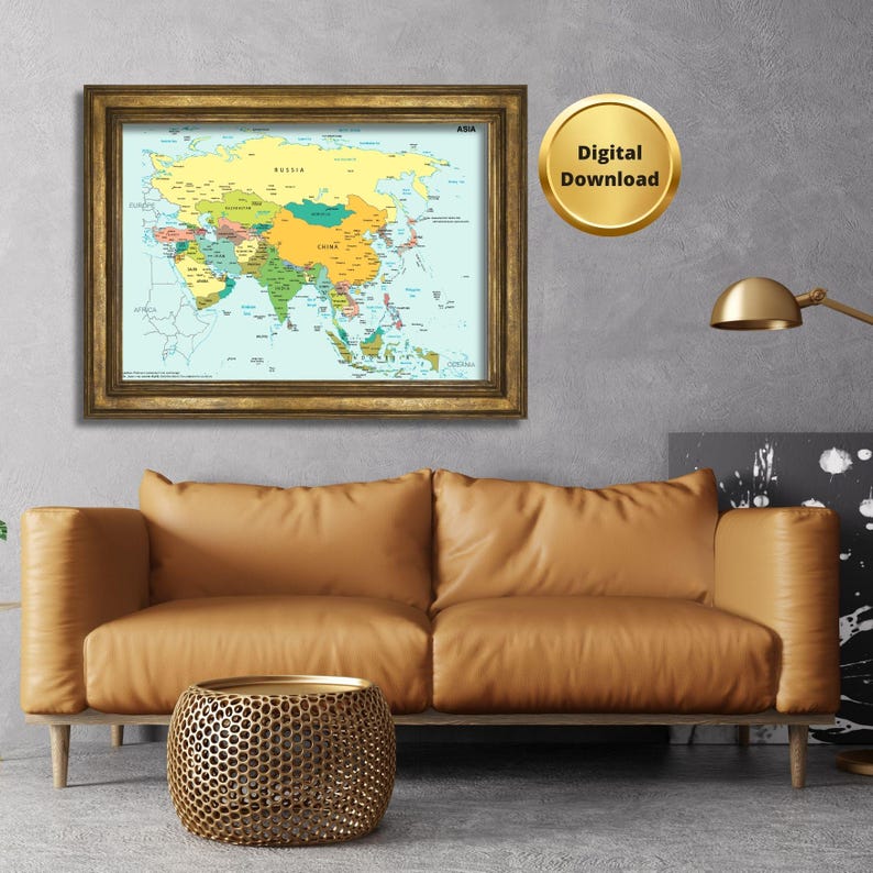 May include: A framed map of Asia with a gold-colored frame hangs on a gray wall. The map is colorful, with each country in a different color. A gold-colored digital download badge is next to the map. Below the map is a brown leather couch and a gold-colored side table.