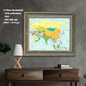 May include: A framed map of Asia with a gold-colored frame hangs on a gray wall. The map is colorful, with countries in different shades. The text "3 Files Included: SVG (editable), PDF, JPG 300 dpi (9933 x 7016 px)" is visible.