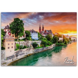 May include: A scenic view of Basel, Switzerland, at sunset. The city skyline is visible across the Rhine River, with a church and buildings in the foreground. The sky is a vibrant orange and pink, with clouds reflecting the warm light.