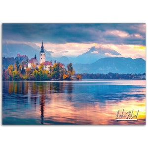May include: A picturesque view of Lake Bled in Slovenia, featuring a small island with a church and a bell tower. The lake is calm and reflective, with a mountain range in the background. The sky is a mix of blue and pink, with clouds.