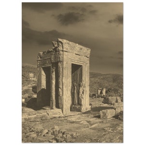May include: A black and white photograph of an ancient stone structure with a doorway. The structure is partially ruined and is located in a desert landscape.
