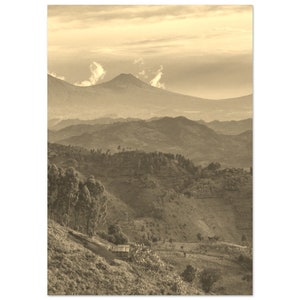 May include: A sepia-toned photograph of a mountainous landscape with a small wooden hut in the foreground. The mountains are covered in trees and vegetation, and there is a distant mountain range in the background. The sky is a light brown color, and there are wispy clouds in the distance.