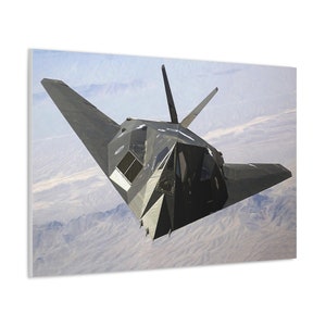 May include: A black and gray stealth fighter jet flies over a desert landscape. The jet has a distinctive angular design and is flying low to the ground.