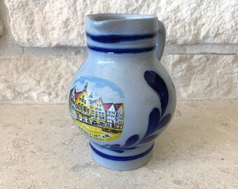 May include: A small blue and white ceramic pitcher with a blue and white floral design and a scene of buildings with the text "FRANKFURT AM MAIN" on the front.