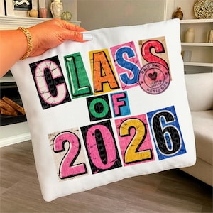May include: White square cushion featuring the text "CLASS OF 2026" in colourful, block-style letters. The cushion also has a pink stamp that says "ORIGINAL HEART & SOUL CO DESIGNER".