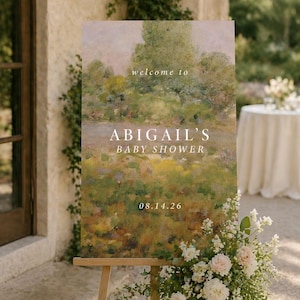 K&ouml;nnte beinhalten: Eine Holzstaffelei zeigt ein Schild mit dem Text "welcome to ABIGAIL'S BABY SHOWER 08.14.26". Das Schild zeigt ein Landschaftsgem&auml;lde in Gr&uuml;n-, Gelb- und Braunt&ouml;nen. Wei&szlig;e und rosa Blumen schm&uuml;cken die Basis der Staffelei.