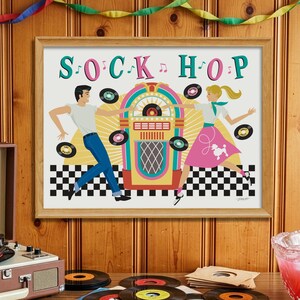 May include: A framed wall print titled SOCK HOP featuring a colorful illustration of two people dancing next to a jukebox on a black and white checkered floor. The artwork includes floating vinyl records and musical notes against a yellow sunburst.