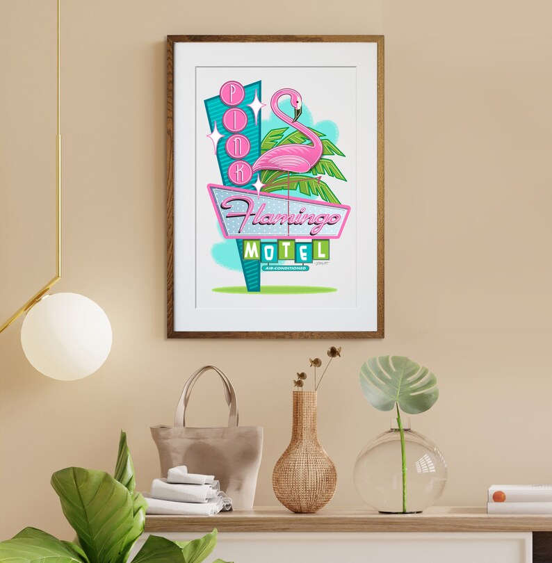 Puede incluir: Una ilustraci&oacute;n enmarcada de un flamenco rosa de pie en un letrero de motel retro que dice "Flamingo Motel" con la palabra "Pink" en luces de ne&oacute;n sobre el flamenco. El letrero est&aacute; situado contra un cielo azul con palmeras.