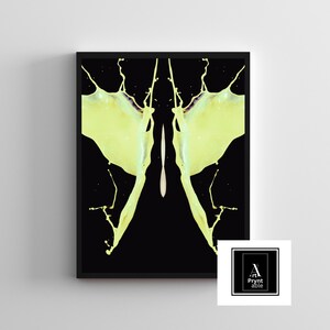 May include: A framed art print featuring a symmetrical design of yellow paint splashes against a black background. The artwork has a modern aesthetic, with a splash-like design. The print is in a black frame, and a logo is in the bottom right corner.