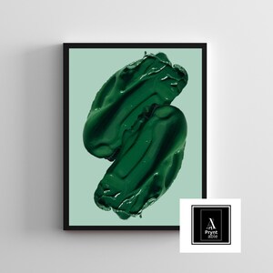 May include: A framed art print featuring two abstract, glossy, dark green paint strokes against a light green background. The artwork is in a black frame. The lower right corner has a white square with the text "Art Prynt Able" in a black frame.