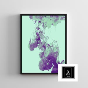 May include: Abstract art print in a black frame. The artwork features a blend of purple and green ink swirling against a light green background. The image has a modern aesthetic, suitable for home decor.