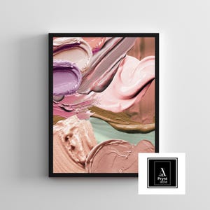 May include: Abstract art print featuring thick brushstrokes of various colors, including pink, purple, and brown. The artwork is framed in a black border and includes a logo in the bottom right corner. The image showcases a close-up of the textured paint.