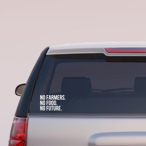 May include: A white car with a black rear window sticker that reads "NO FARMERS. NO FOOD. NO FUTURE."