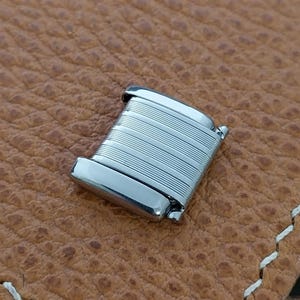 May include: A silver watch band clasp with a ridged design.