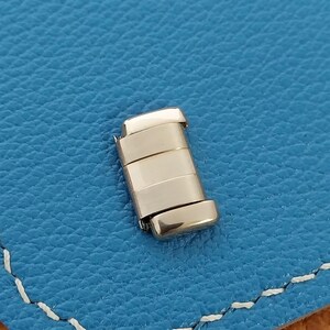 May include: A silver metal watch band link with a polished finish.